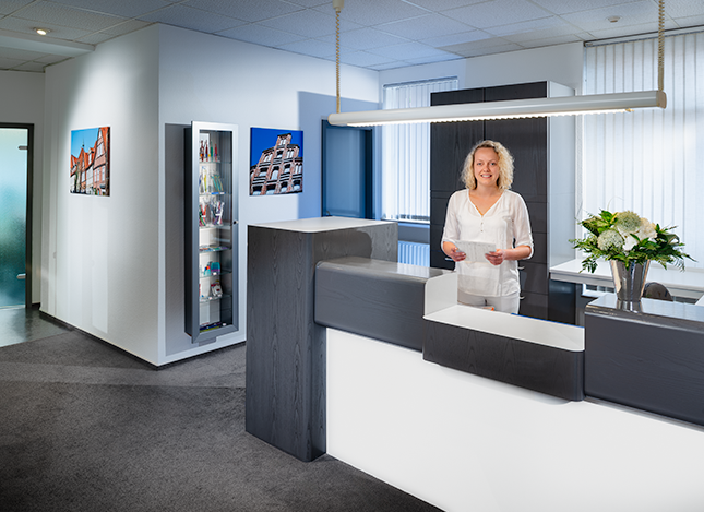 Helferin am Empfang der Zahnarztpraxis hält eine Patientenkarte - Dr. Zennecke in Lüneburg